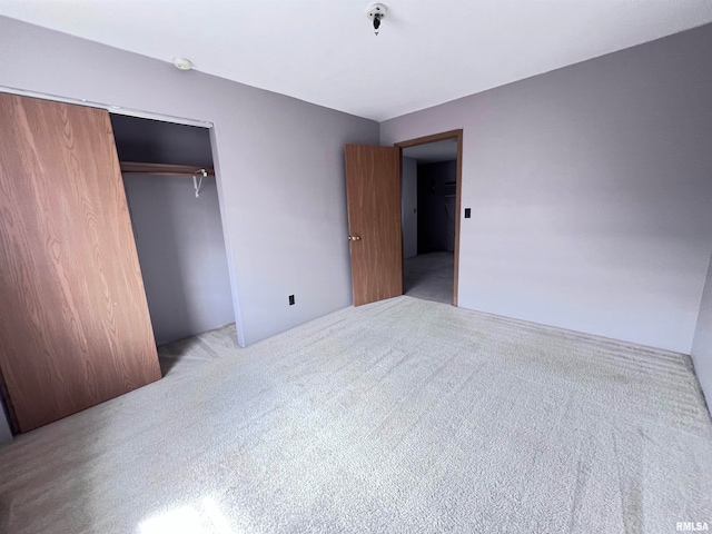 unfurnished bedroom featuring light colored carpet and a closet