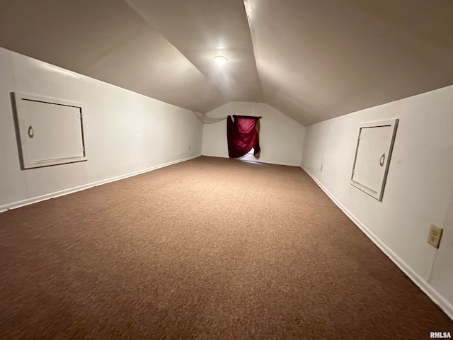 additional living space featuring lofted ceiling and dark colored carpet