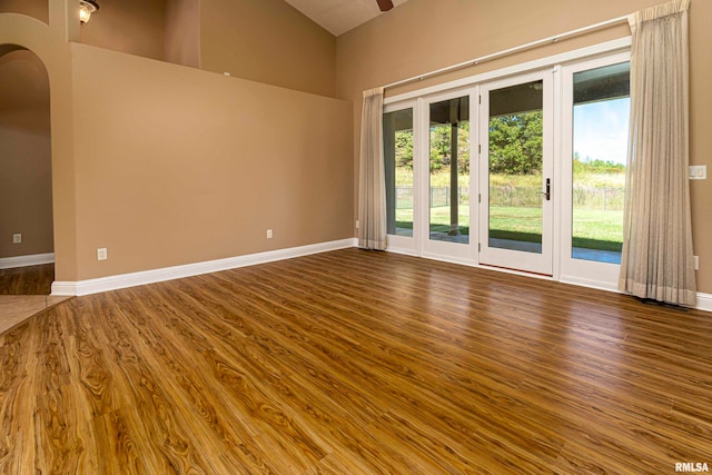 empty room featuring plenty of natural light, high vaulted ceiling, and hardwood / wood-style flooring