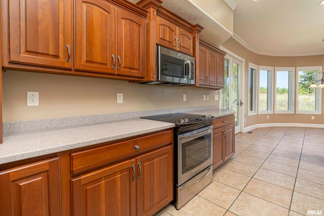 kitchen with ornamental molding, light tile patterned floors, and stainless steel appliances