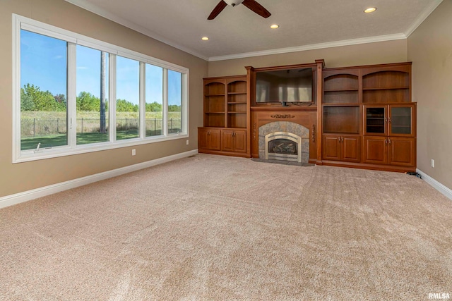 unfurnished living room featuring a tile fireplace, carpet, crown molding, and ceiling fan