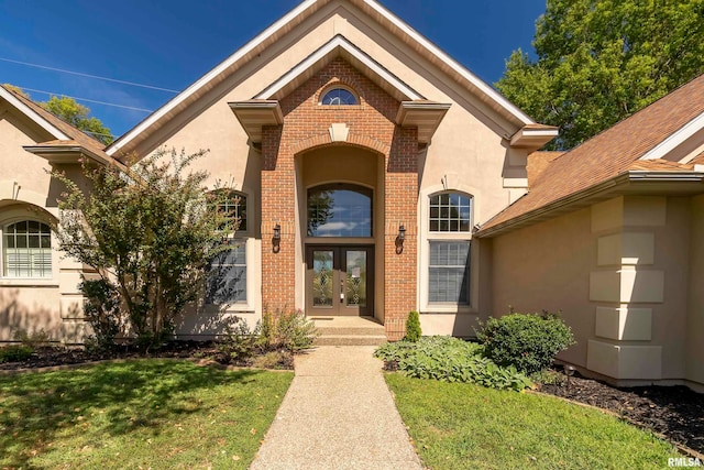 view of exterior entry featuring a lawn and french doors