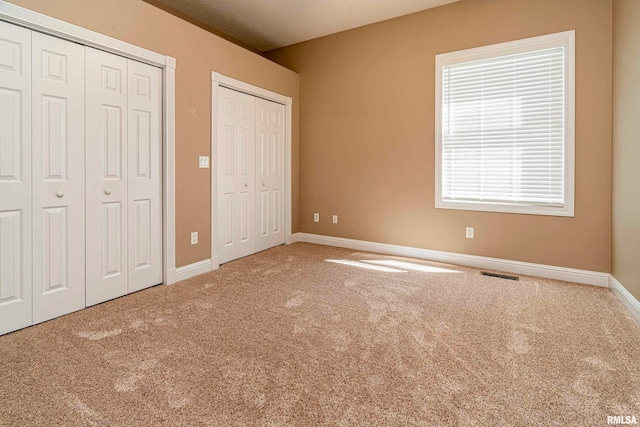 unfurnished bedroom featuring multiple closets and carpet flooring