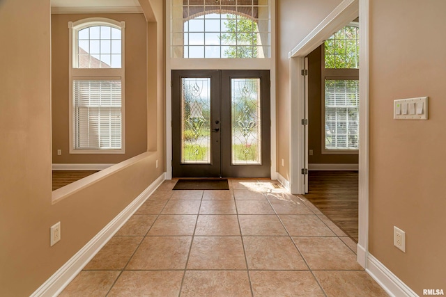 entrance foyer with a towering ceiling, light tile patterned floors, and french doors