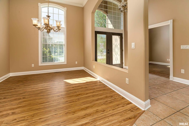 empty room with wood-type flooring, a notable chandelier, and a wealth of natural light