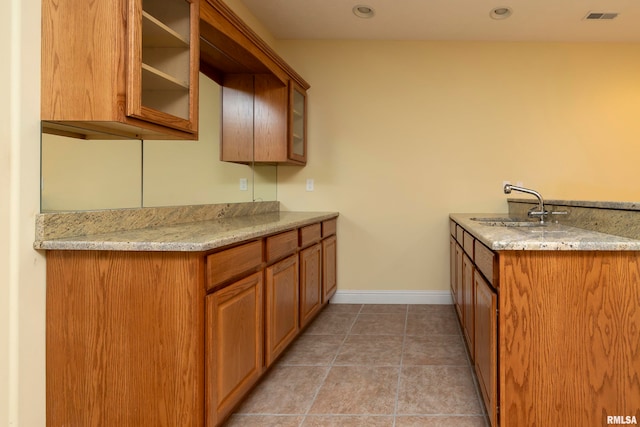 kitchen featuring sink, light tile patterned floors, and light stone counters