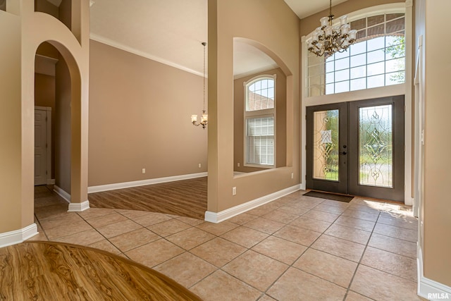 foyer entrance featuring a high ceiling, a chandelier, french doors, and light hardwood / wood-style flooring