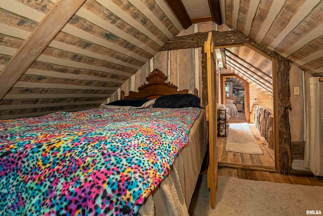 bedroom featuring lofted ceiling, wood walls, and hardwood / wood-style flooring