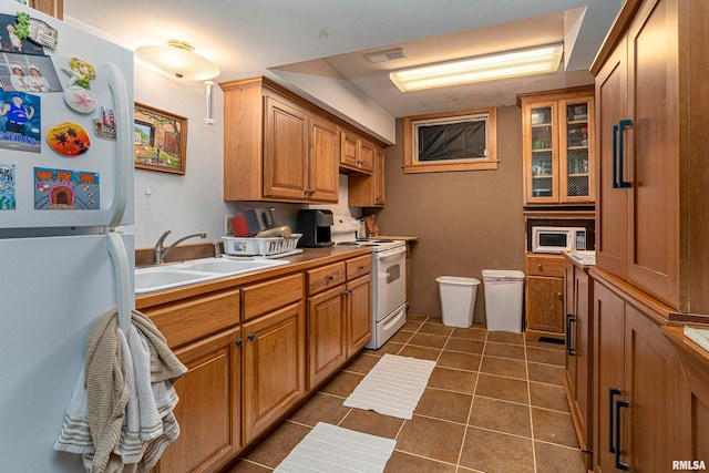 kitchen with dark tile patterned flooring, sink, and white appliances