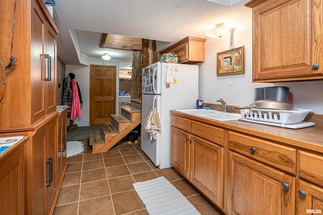 kitchen featuring white refrigerator, dark tile patterned flooring, and sink