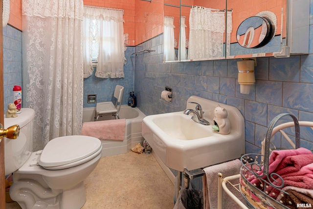 full bathroom with tile walls, toilet, sink, and shower / bath combo with shower curtain