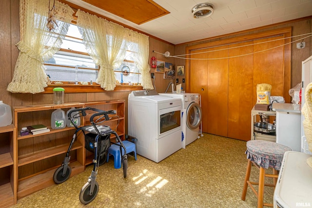 clothes washing area with wood walls, light colored carpet, and washer and dryer