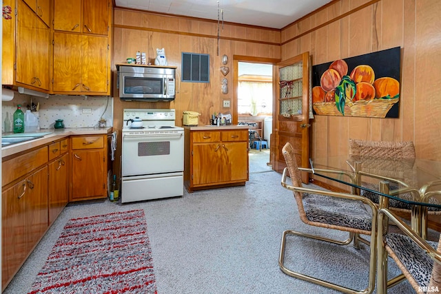 kitchen with ornamental molding, wood walls, and white electric stove