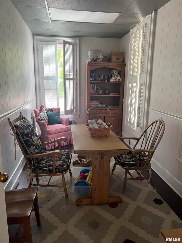 dining area with a paneled ceiling and wooden walls