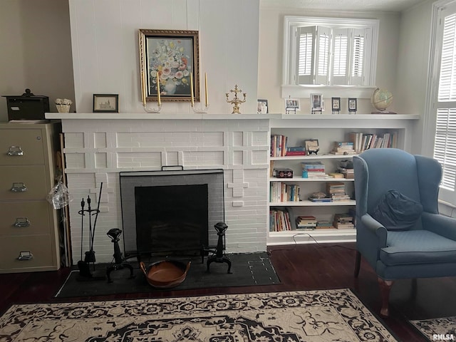 living area with a wealth of natural light, dark hardwood / wood-style floors, and a brick fireplace