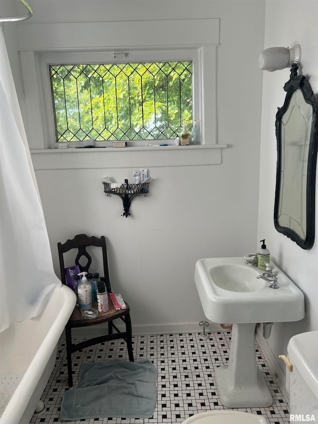 bathroom with toilet, a wealth of natural light, and tile patterned flooring