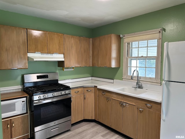 kitchen with light hardwood / wood-style flooring, white appliances, and sink