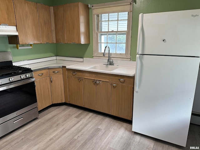 kitchen featuring light hardwood / wood-style flooring, white fridge, stainless steel range, and sink