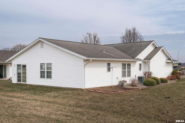 back of house with roof with shingles, a yard, and central AC unit