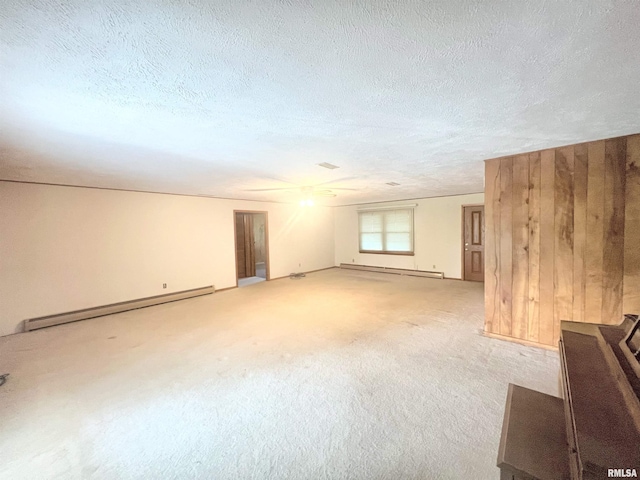 carpeted spare room featuring a textured ceiling, baseboard heating, and wooden walls