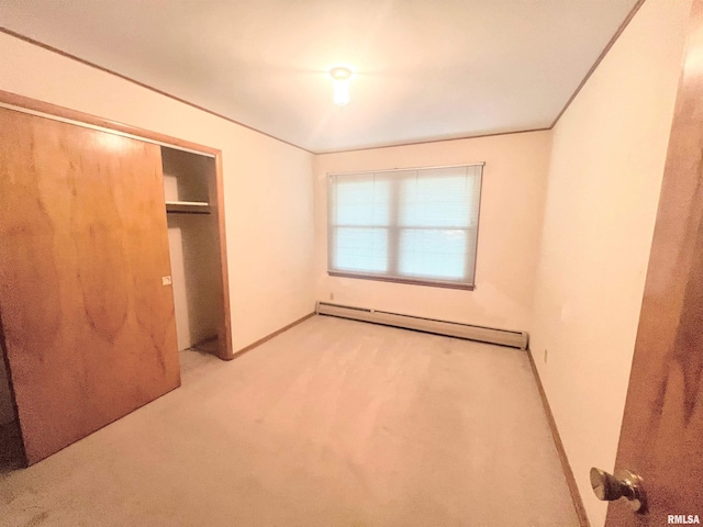 unfurnished bedroom featuring light colored carpet, baseboard heating, and a closet