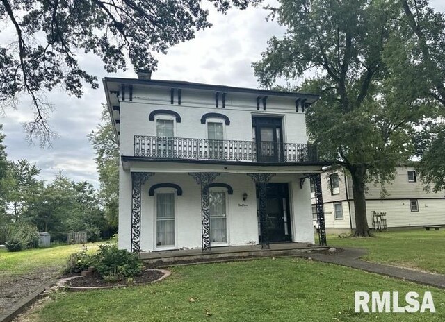 italianate house with a balcony, a porch, and a front lawn