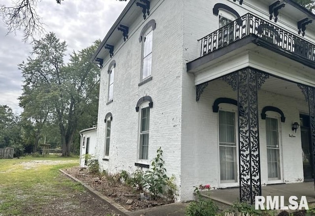 view of side of property featuring a lawn and a balcony