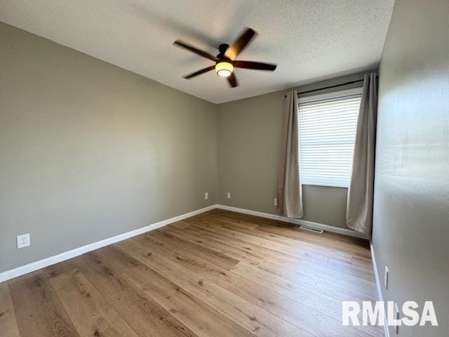 spare room featuring light wood-type flooring, ceiling fan, and a textured ceiling