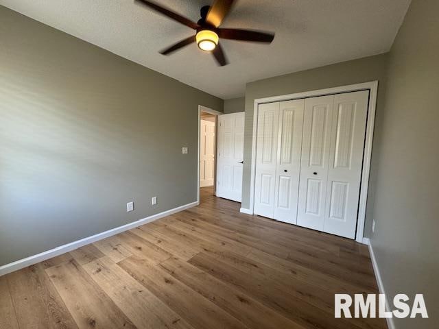 unfurnished bedroom with a textured ceiling, hardwood / wood-style flooring, ceiling fan, and a closet