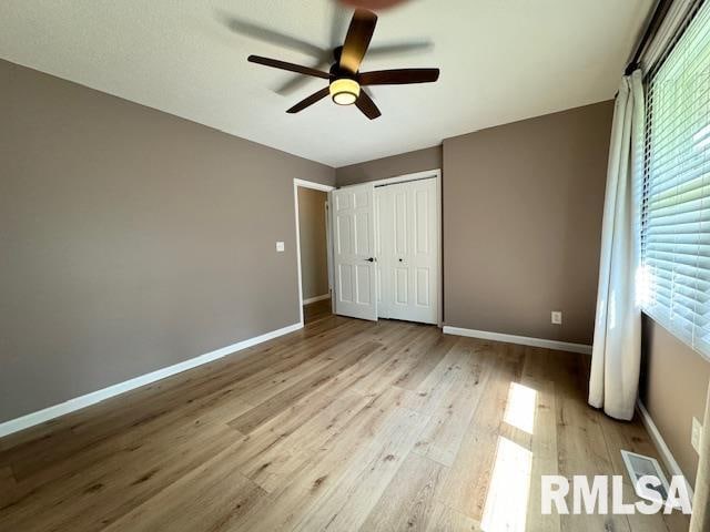 unfurnished bedroom featuring a closet, ceiling fan, a fireplace, and light hardwood / wood-style floors