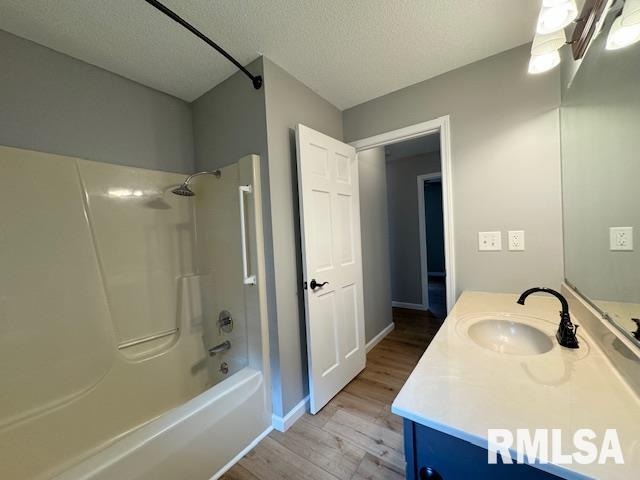 bathroom featuring vanity, a textured ceiling, hardwood / wood-style floors, and  shower combination