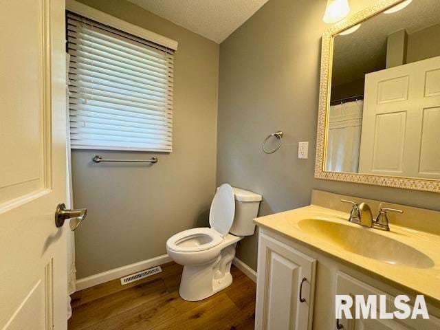 bathroom featuring a textured ceiling, vanity, toilet, and hardwood / wood-style floors