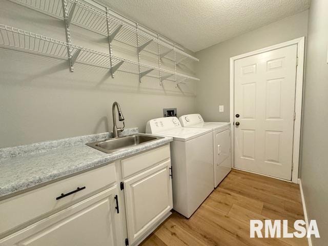 laundry room with light hardwood / wood-style flooring, separate washer and dryer, a textured ceiling, and sink