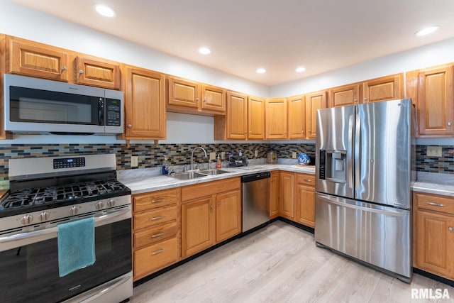 kitchen featuring light hardwood / wood-style flooring, backsplash, appliances with stainless steel finishes, and sink