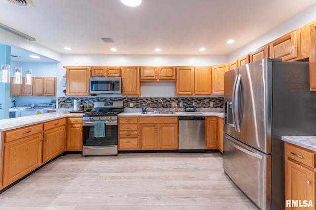 kitchen with hanging light fixtures, sink, light hardwood / wood-style flooring, stainless steel appliances, and decorative backsplash