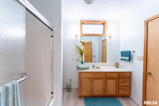 bathroom with walk in shower, vanity, and hardwood / wood-style floors