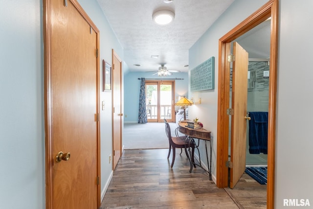 hall with a textured ceiling and dark hardwood / wood-style flooring