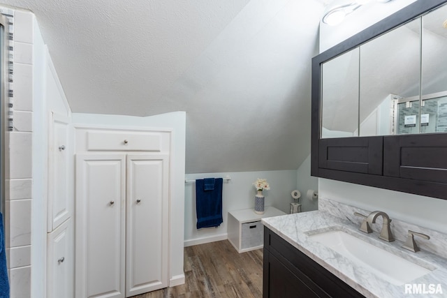 bathroom featuring a textured ceiling, wood-type flooring, lofted ceiling, and vanity