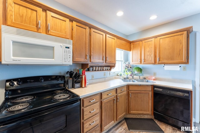 kitchen with black appliances, sink, and light hardwood / wood-style flooring