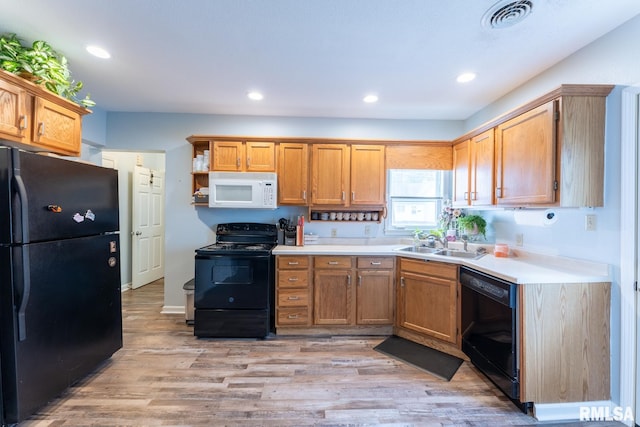 kitchen with black appliances, light hardwood / wood-style floors, and sink