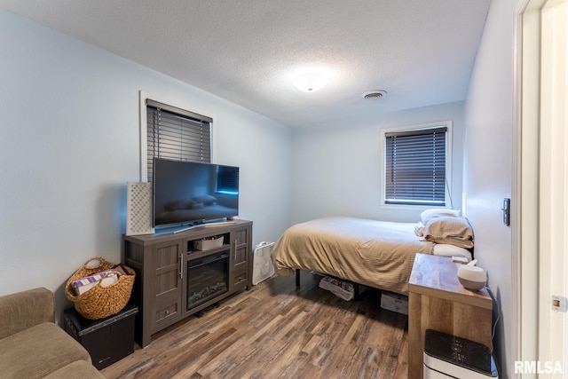 bedroom with a textured ceiling and wood-type flooring