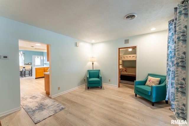 sitting room featuring light wood-type flooring and a textured ceiling