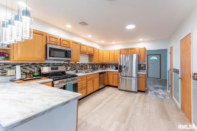 kitchen with pendant lighting, light wood-type flooring, tasteful backsplash, kitchen peninsula, and stainless steel appliances