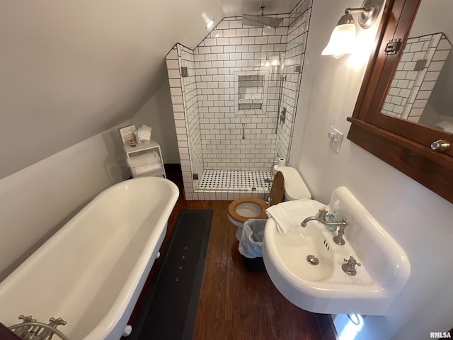 bathroom featuring wood-type flooring, tiled shower, vaulted ceiling, and toilet