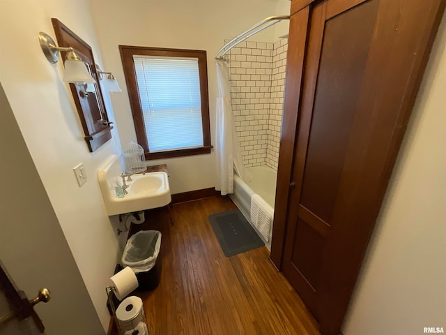 bathroom with wood-type flooring, shower / bath combo with shower curtain, and sink