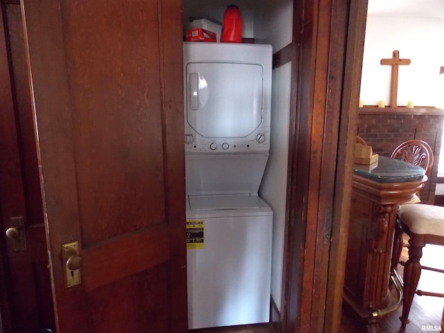 laundry room featuring stacked washer / dryer and hardwood / wood-style flooring