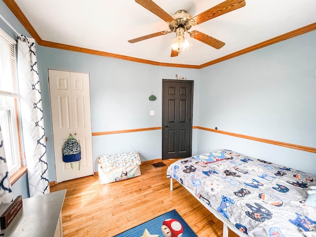 bedroom with ornamental molding, wood-type flooring, a closet, and ceiling fan