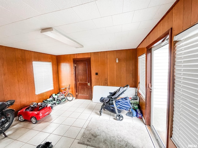 misc room featuring wooden walls and light tile patterned floors