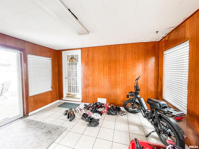 exercise room featuring wooden walls and light tile patterned floors