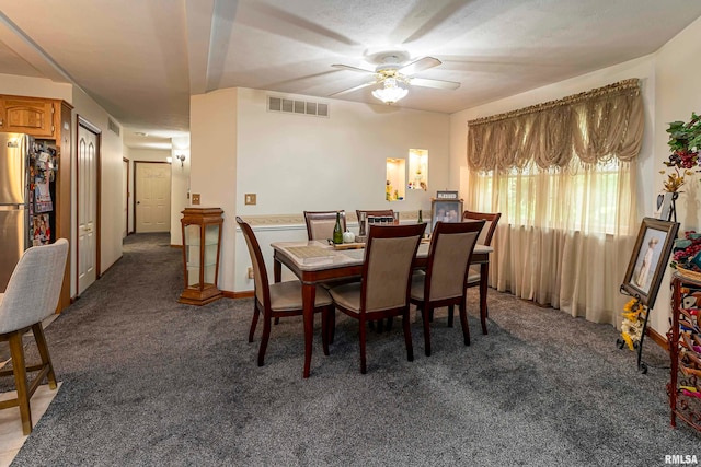 dining space featuring dark colored carpet and ceiling fan